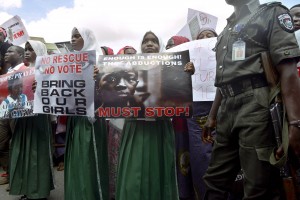 A policeman stand beside children holding as members of Lagos based civil society groups hold rally calling for the release of missing Chibok school girls at the state government house, in Lagos, Nigeria, on May 5, 2014. Boko Haram on Monday claimed the abduction of hundreds of schoolgirls in northern Nigeria that has triggered international outrage, threatening to sell them as "slaves". "I abducted your girls," the Islamist group's leader Abubakar Shekau said in the 57-minute video obtained by AFP, referring to the 276 students kidnapped from their boarding school in Chibok, Borno state, three weeks ago. AFP PHOTO / PIUS UTOMI EKPEI